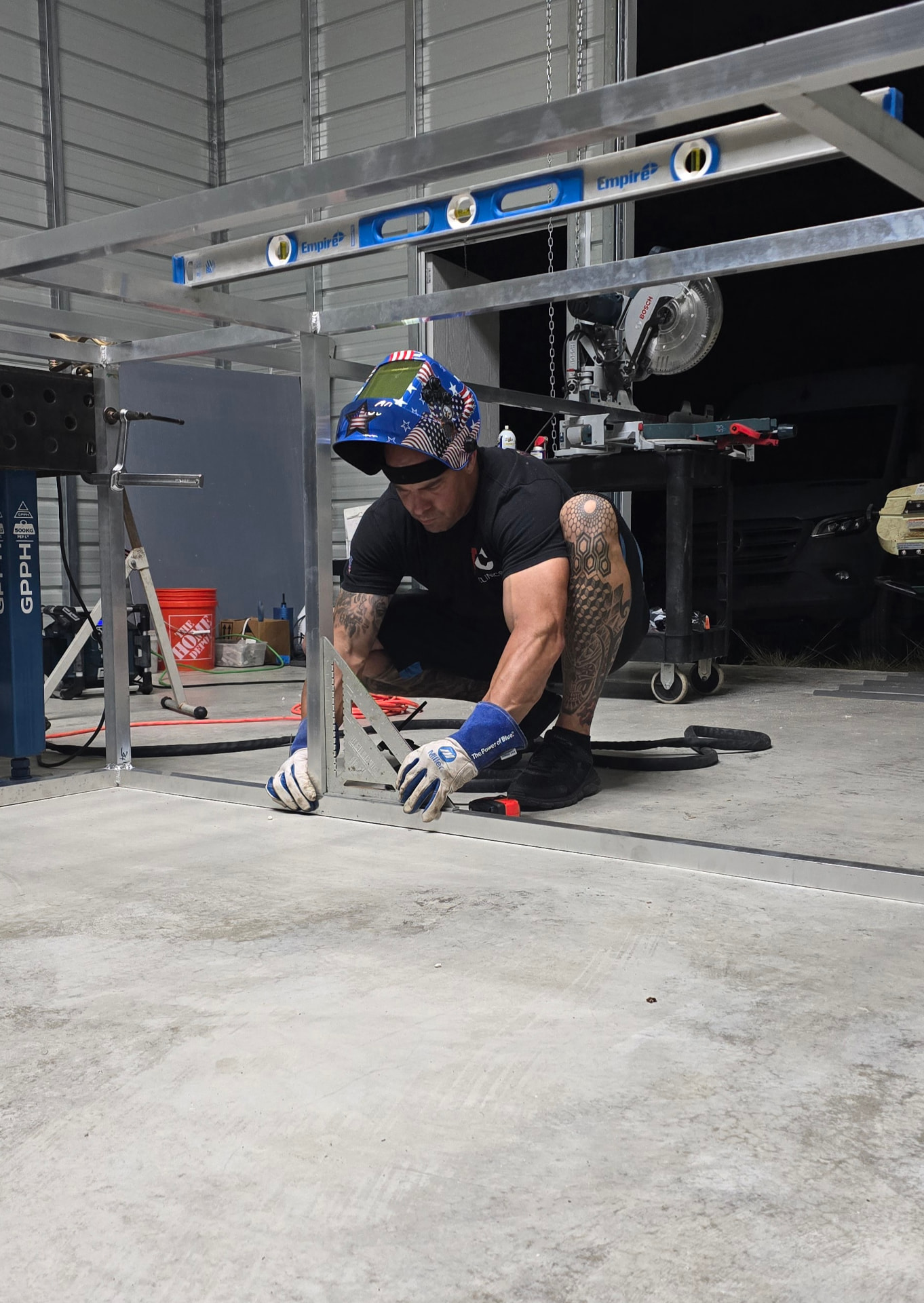 R&S welder in a welding helmet squaring an aluminum frame on the shop floor